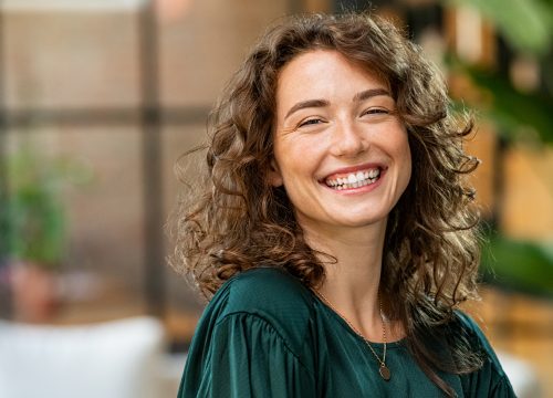 Photo of a smiling woman with curly hair wearing an emerald shirt