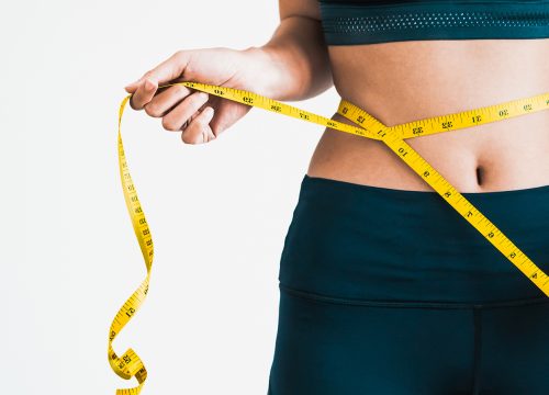 Photo of a woman's waistline with measuring tape