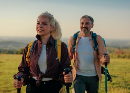 Photo of an older couple hiking in a green field